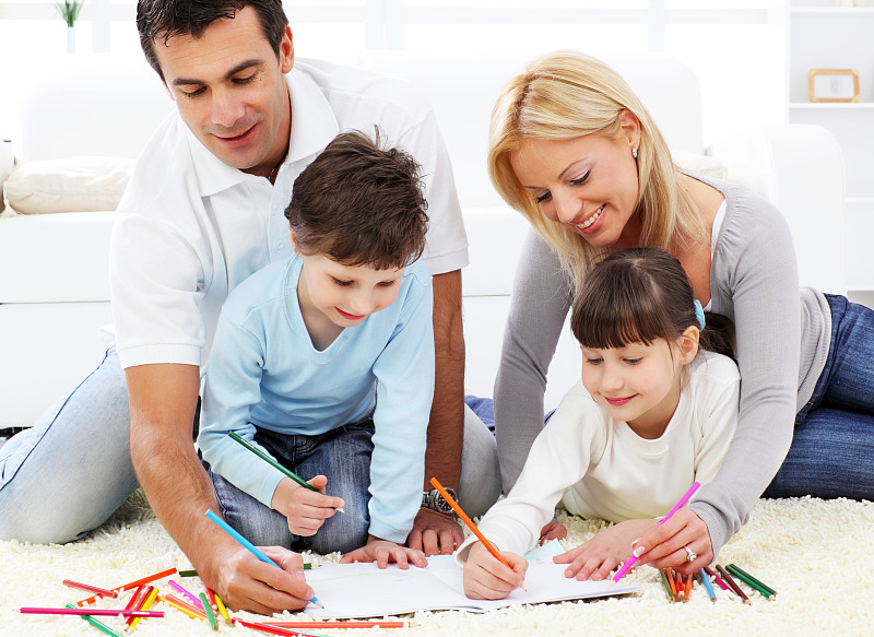 幸福的家庭。家长带着孩子用彩色铅笔画画。图片下载