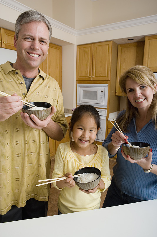 一个家庭在厨房里拿着碗米饭和筷子图片下载