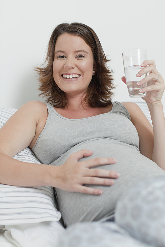 女人抱着怀孕的肚子躺在床上图片下载