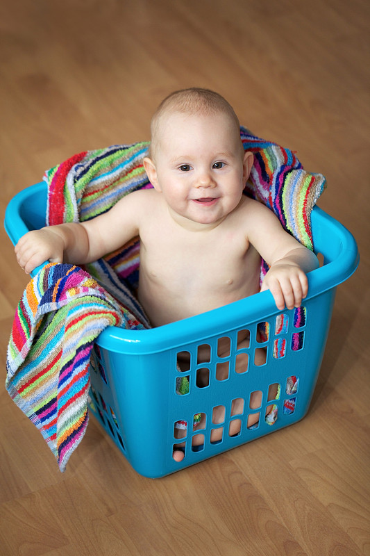 小女孩坐在洗衣篮里。图片下载