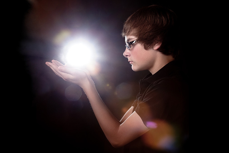 十几岁的男孩拿着发光的光或能量图片下载