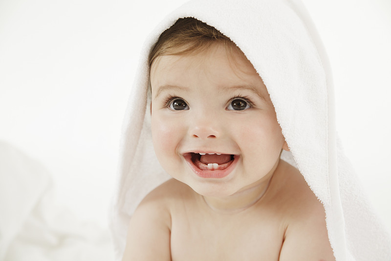 裹着毛巾微笑的婴儿，特写图片下载