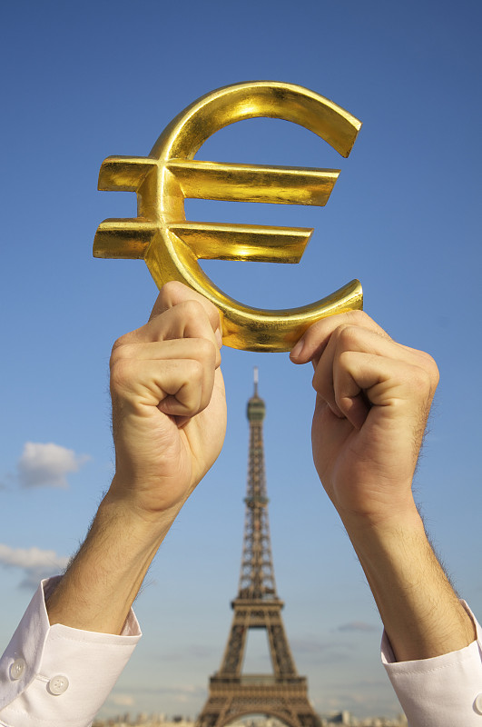埃菲尔铁塔旁的手握着欧元黄金货币符号图片下载