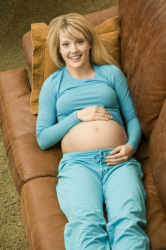 孕妇躺在客厅的沙发上，面带微笑，居高临下图片下载