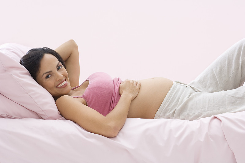 孕妇躺在床上，微笑着，画像图片下载
