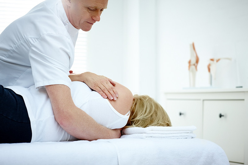 一位男性理疗师在按摩一位年长女性的背部图片素材