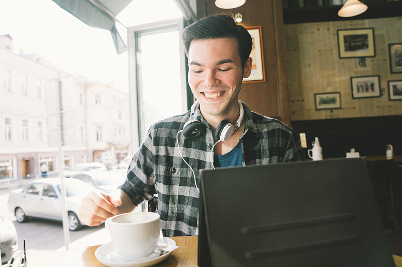 快乐的年轻人在咖啡店用平板电脑图片下载