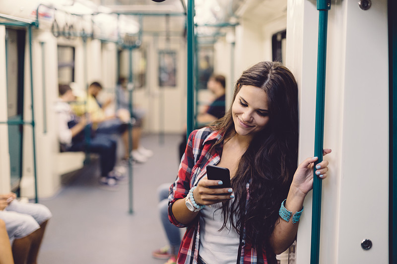 十几岁的女孩在乘坐地铁时使用手机图片下载