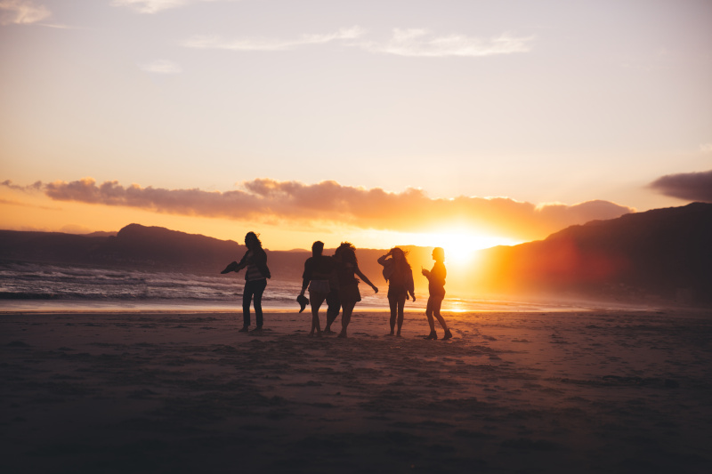 日落时分，沙滩上跳舞的青少年朋友的剪影图片素材