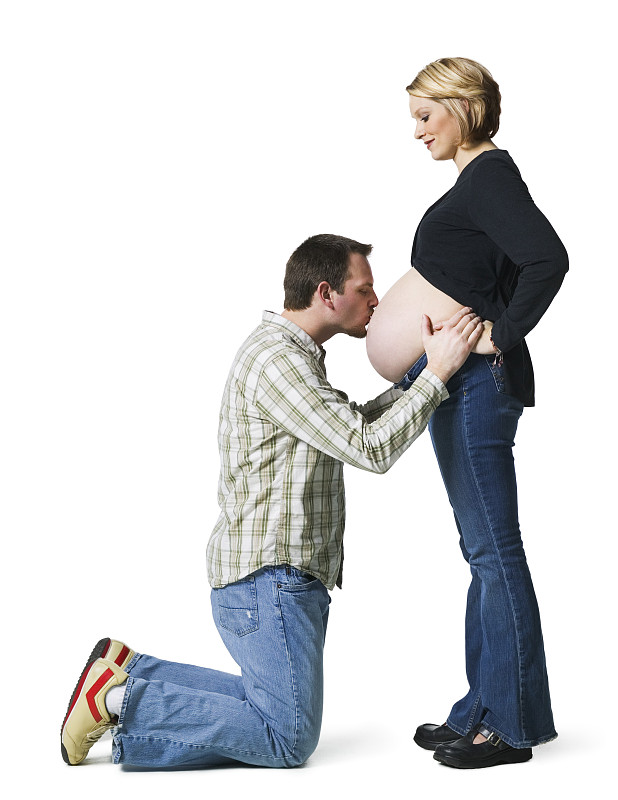 一个中年男人亲吻他怀孕妻子的腹部的侧影图片下载