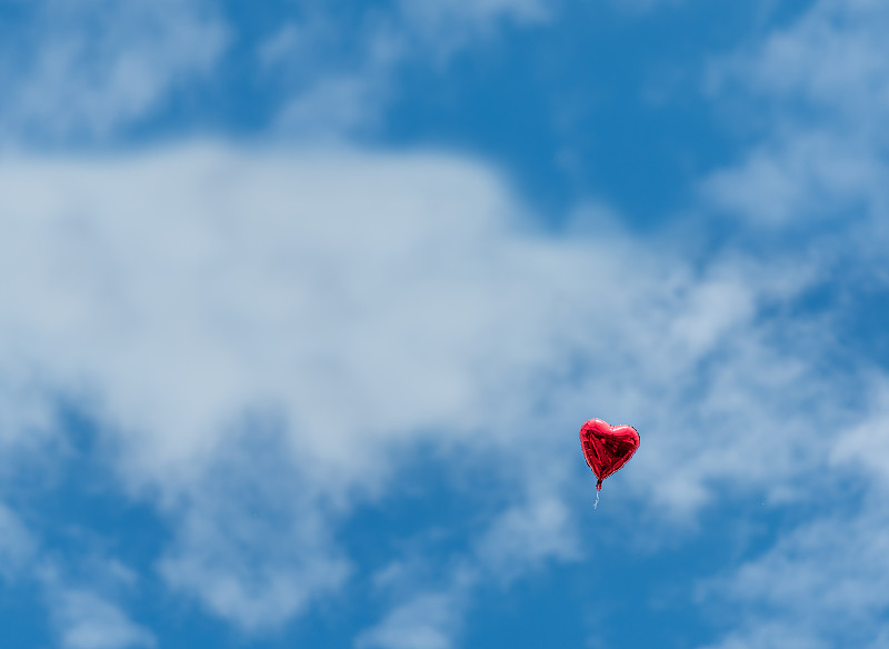 一个红色的心形气球在天空中图片下载