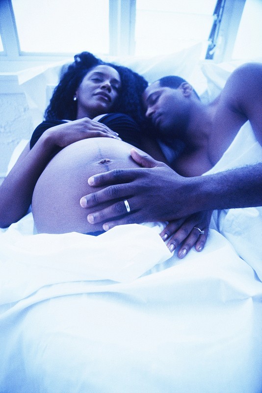 一个男人的手在他怀孕的妻子暴露的肚子上的高角度特写图片下载