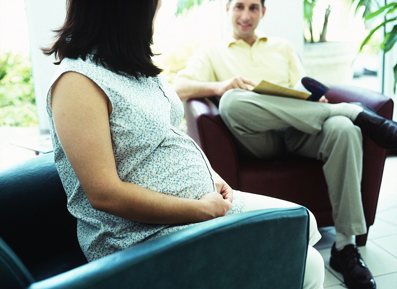 侧面特写的孕妇坐在椅子上和她的丈夫说话图片下载
