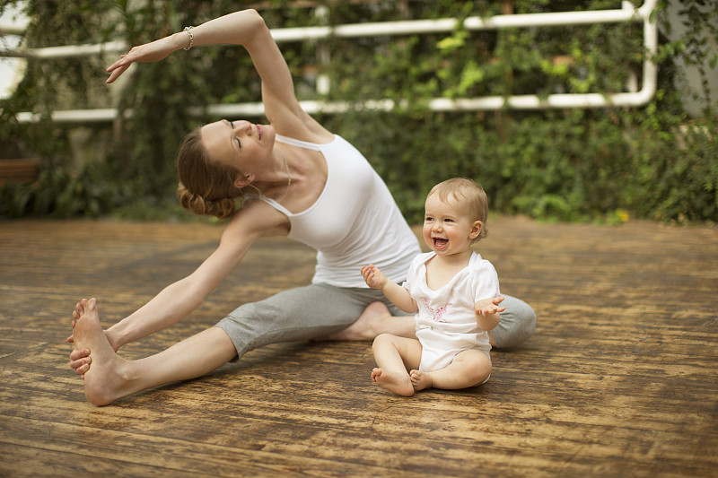 女人做瑜伽锻炼，而婴儿有乐趣图片下载