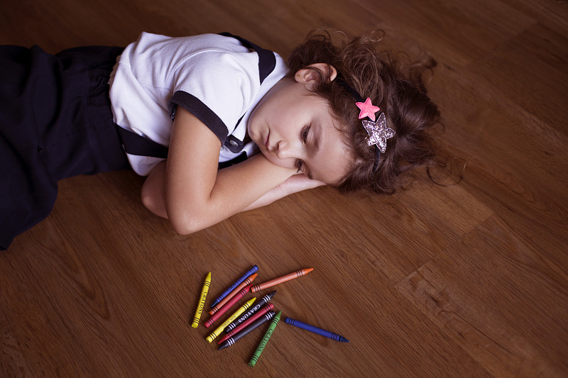 女孩躺在地板上，手里拿着蜡笔图片素材