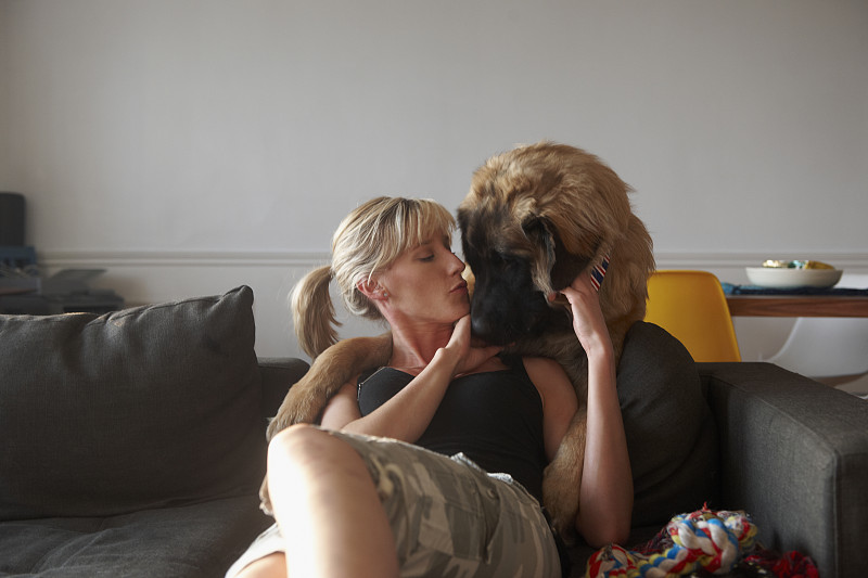 一个白人女人在沙发上亲吻一只狗图片素材