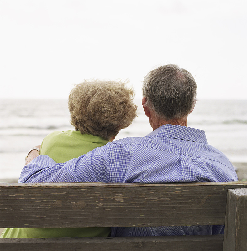 一对夫妇坐在海边的长椅上图片下载