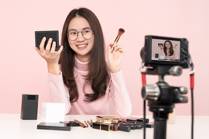亚洲女性专业美容视频博主或博主通过相机在社交媒体上直播化妆教程的病毒视频剪辑。商业在线影响者对社交媒体的概念。在线销售。网上购物图片下载