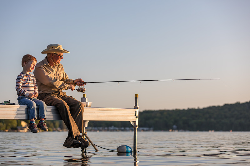 爷爷和孙子在夏天的日落钓鱼图片素材