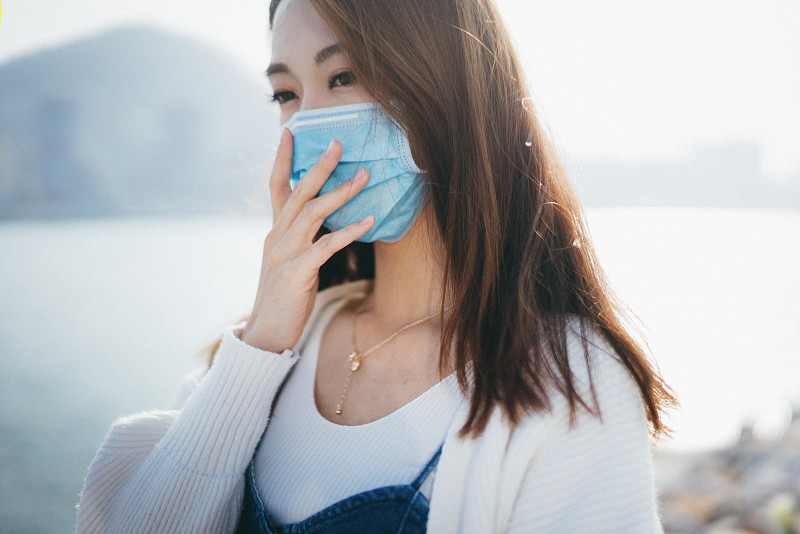 年轻的亚洲妇女戴着防护口罩，以防止冠状病毒的传播，全球卫生紧急疫情爆发图片素材