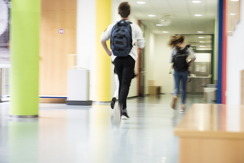 学生们在学校走廊上奔跑。图片素材