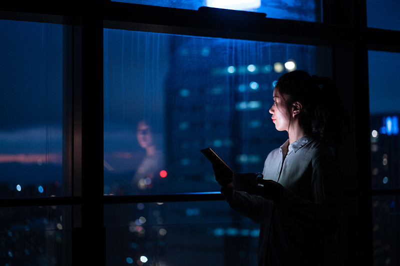 亚洲女性在家里窗户边使用智能手机图片下载