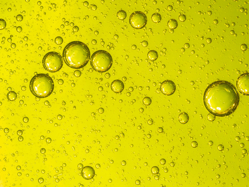 全框架抽象的形状和纹理形成的泡沫和滴油渍在黄色液体背景。图片素材