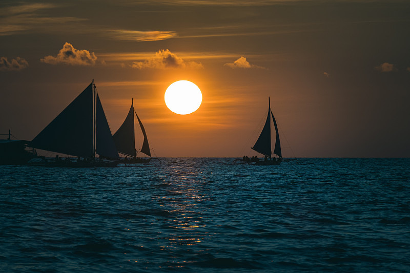 日落时在海上逆天航行的帆船图片素材