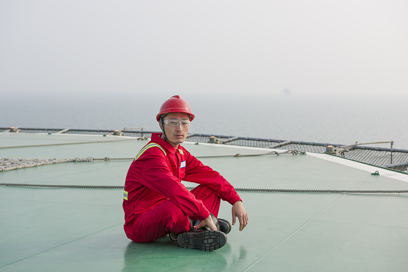 在海上石油钻塔上的生活。海上石油钻井工人在直升机甲板上图片下载