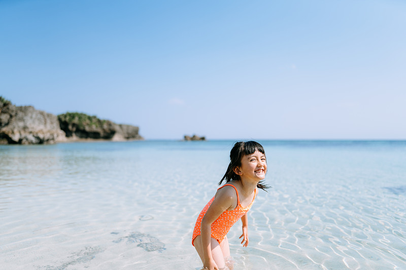 可爱的欧亚女孩玩在热带海滩水，冲绳，日本图片素材