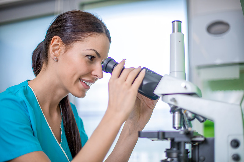 在实验室里研究显微镜的年轻女化学家。图片下载