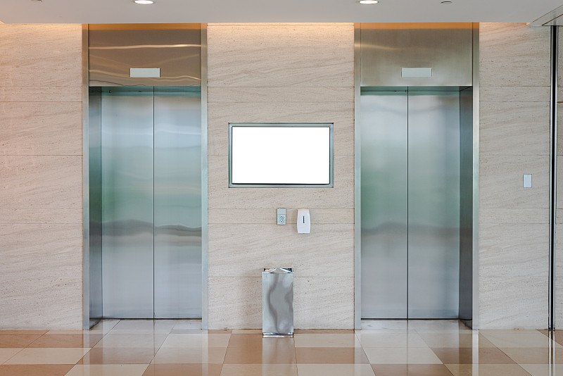 商场和办公楼的两部电梯，上面有白色的广告牌图片素材