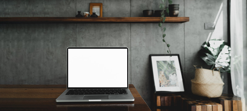 笔记本电脑空白白屏幕上的桌子在咖啡馆的背景。笔记本电脑与空白屏幕上的咖啡店模糊背景。图片下载