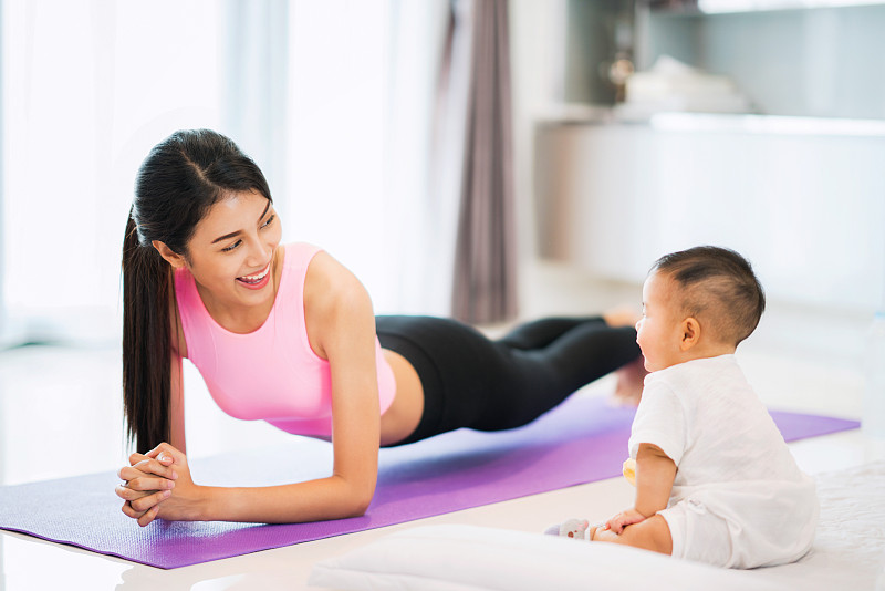 在家锻炼时微笑的女人看着婴儿图片素材