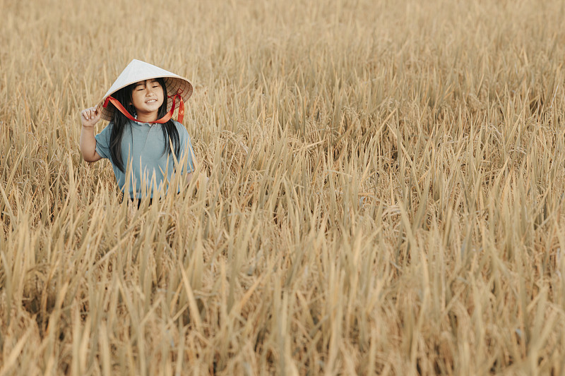 一个亚洲的中国女孩花闲暇时间在稻田在周末早上看相机图片素材