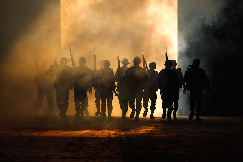 后视图的剪影特种部队士兵与枪和烟雾在光的背景图片素材