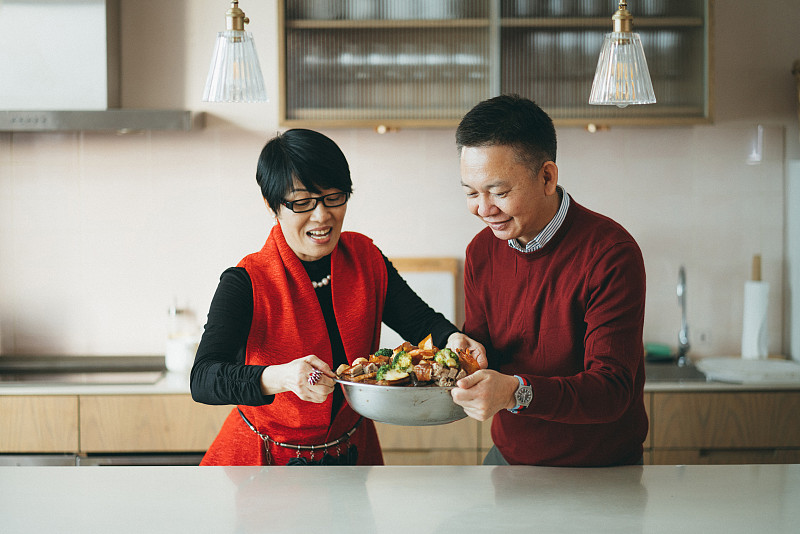 资深亚洲夫妇拿着美味的自制传统中国菜，与家人分享农历新年团圆饭图片素材
