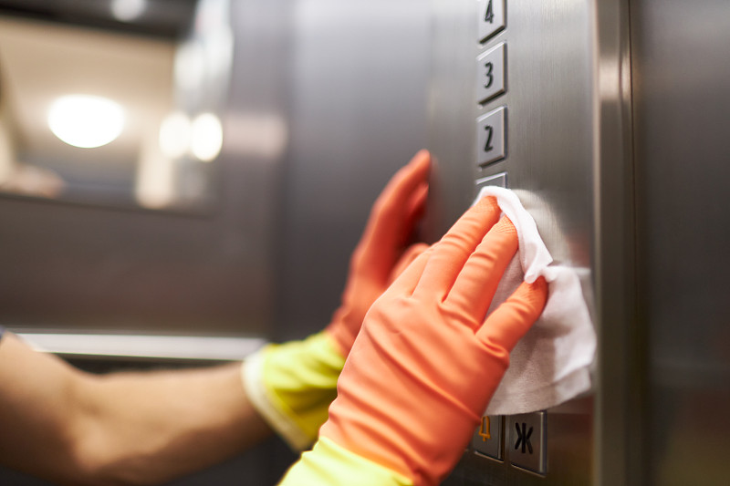 一名女子和一名男子戴着橡胶手套用消毒湿巾消毒和清洁电梯的不同照片摄影图片