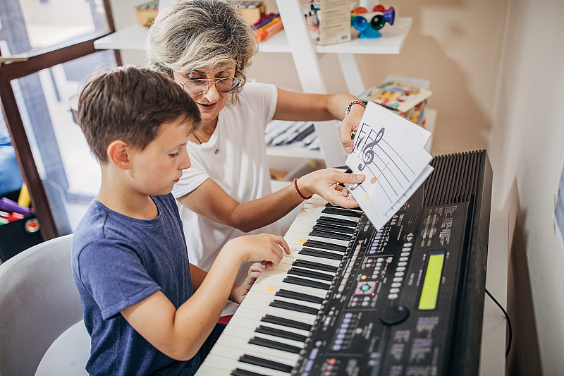在儿童发展中心，男孩和他的音乐老师一起学习如何玩合成器图片下载