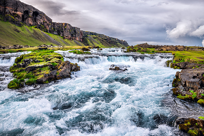 冰岛Fjadrargljufur峡谷湍急的河流景观，水流湍急，绿草苔和多云的天空图片下载