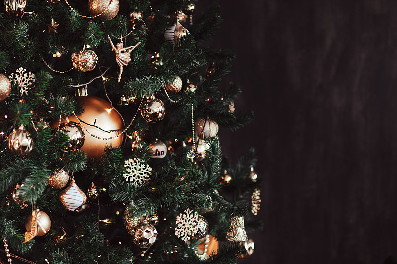 金色的圣诞装饰品在发光的圣诞树在黑色的背景。图片下载