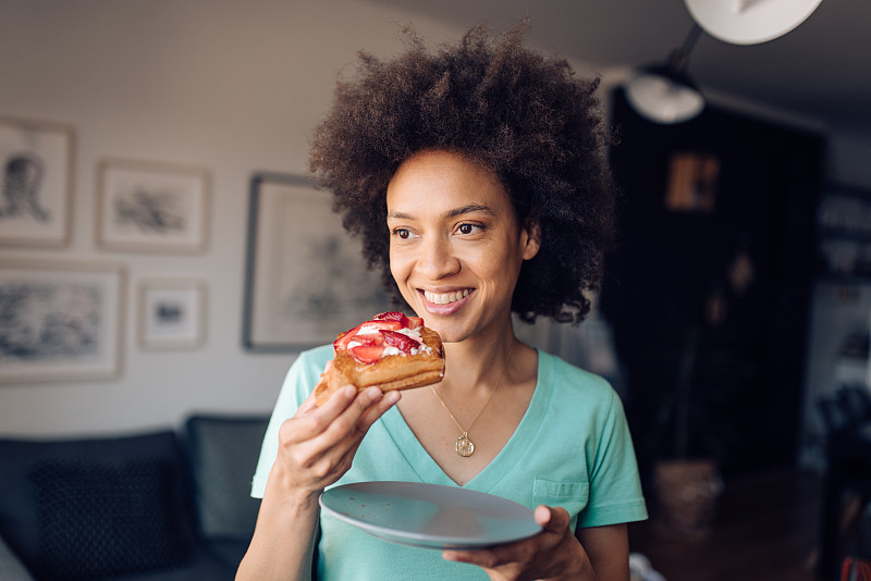 一个年轻的非洲妇女在家里吃早餐的肖像图片下载