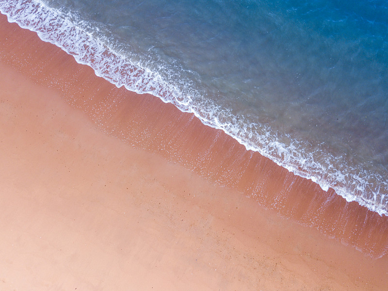 粉色沙滩的鸟瞰图，深蓝色的大海，白色的浪花，夏天的旅行度假概念拷贝空间图片下载