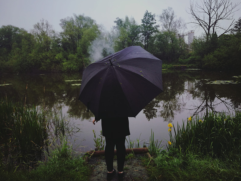 雨季站在潮湿湖面上的人的后视图摄影图片