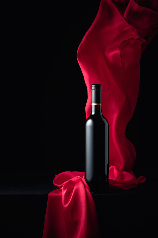Ðottle of red wine with flutters red cloth.图片下载