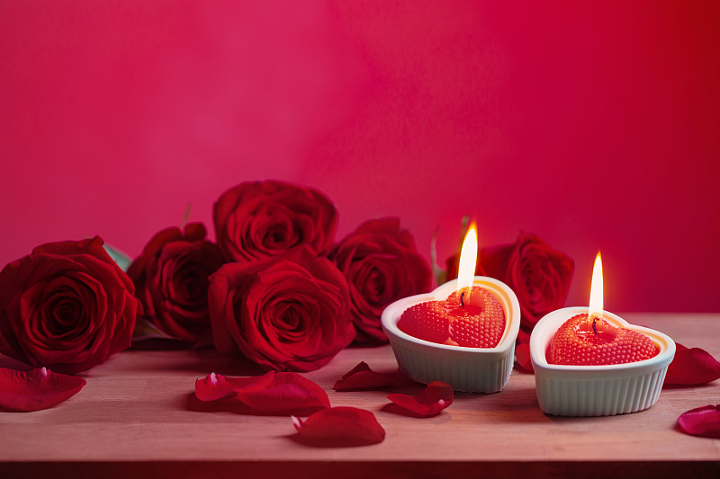 红色的玫瑰，粉色的背景上有燃烧的蜡烛图片下载