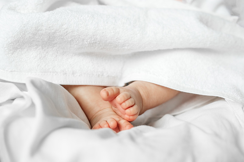 新生儿的脚在白色毯子下。美丽的背景。新生儿和家庭概念。近距离图片下载