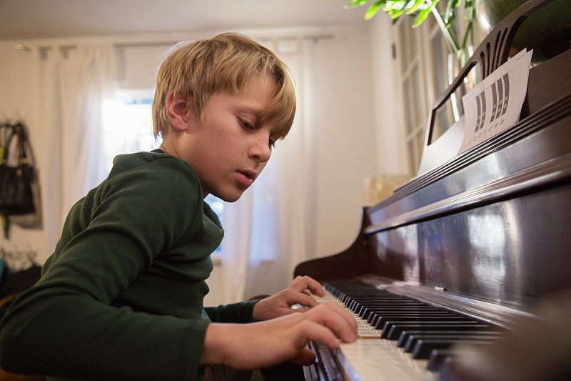 男孩在客厅弹钢琴图片下载