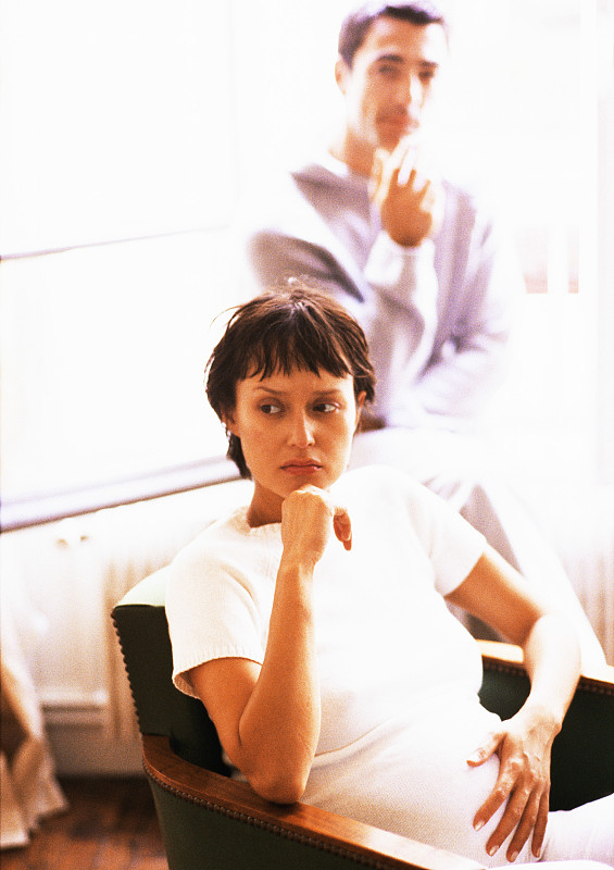孕妇坐在扶手椅上，背景模糊图片下载