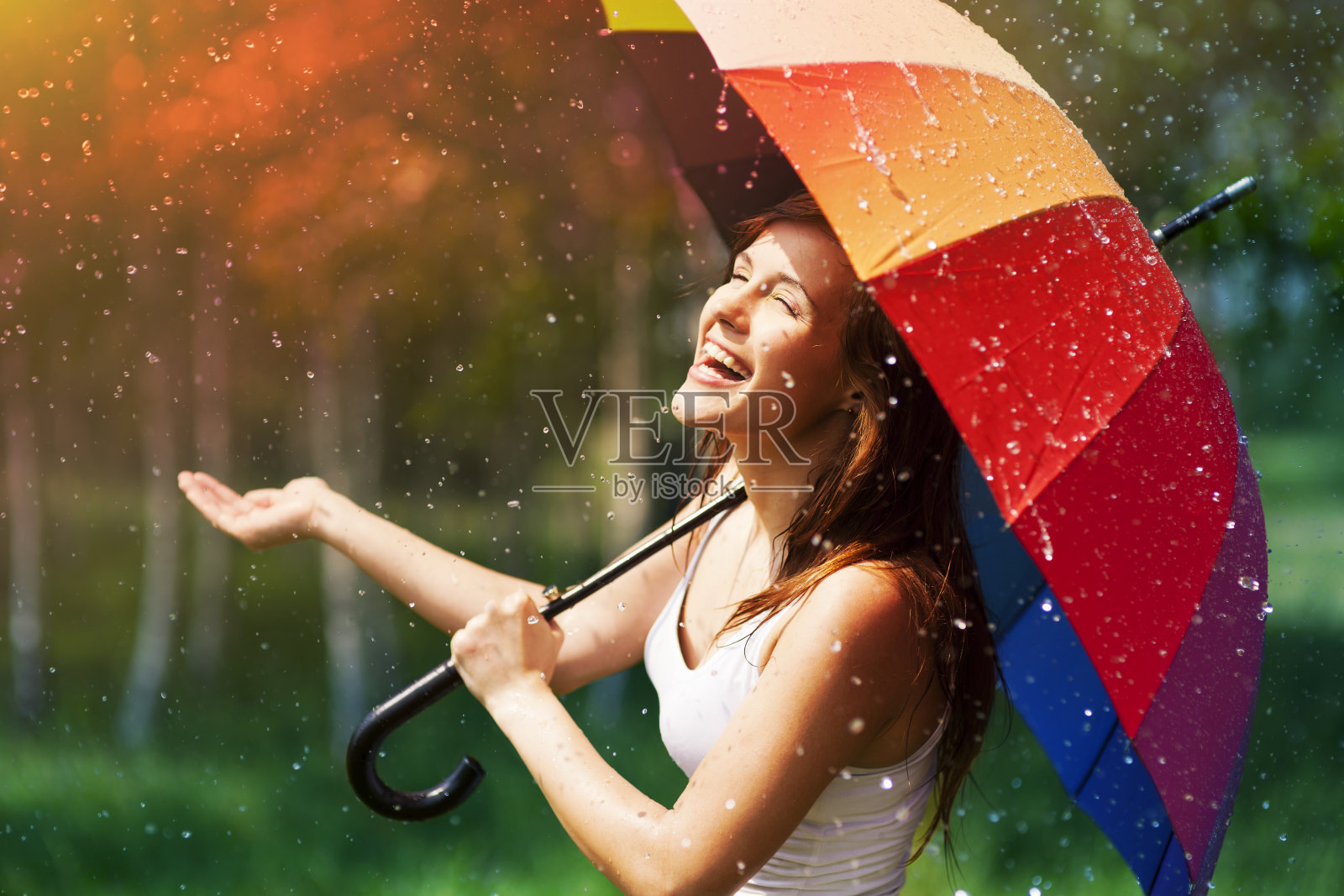 带着伞的笑女人在检查是否下雨照片摄影图片